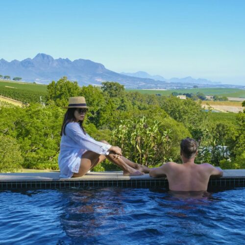 couple in swimming pool looking out over the Vineyards and mountains of Stellenbosch South Africa